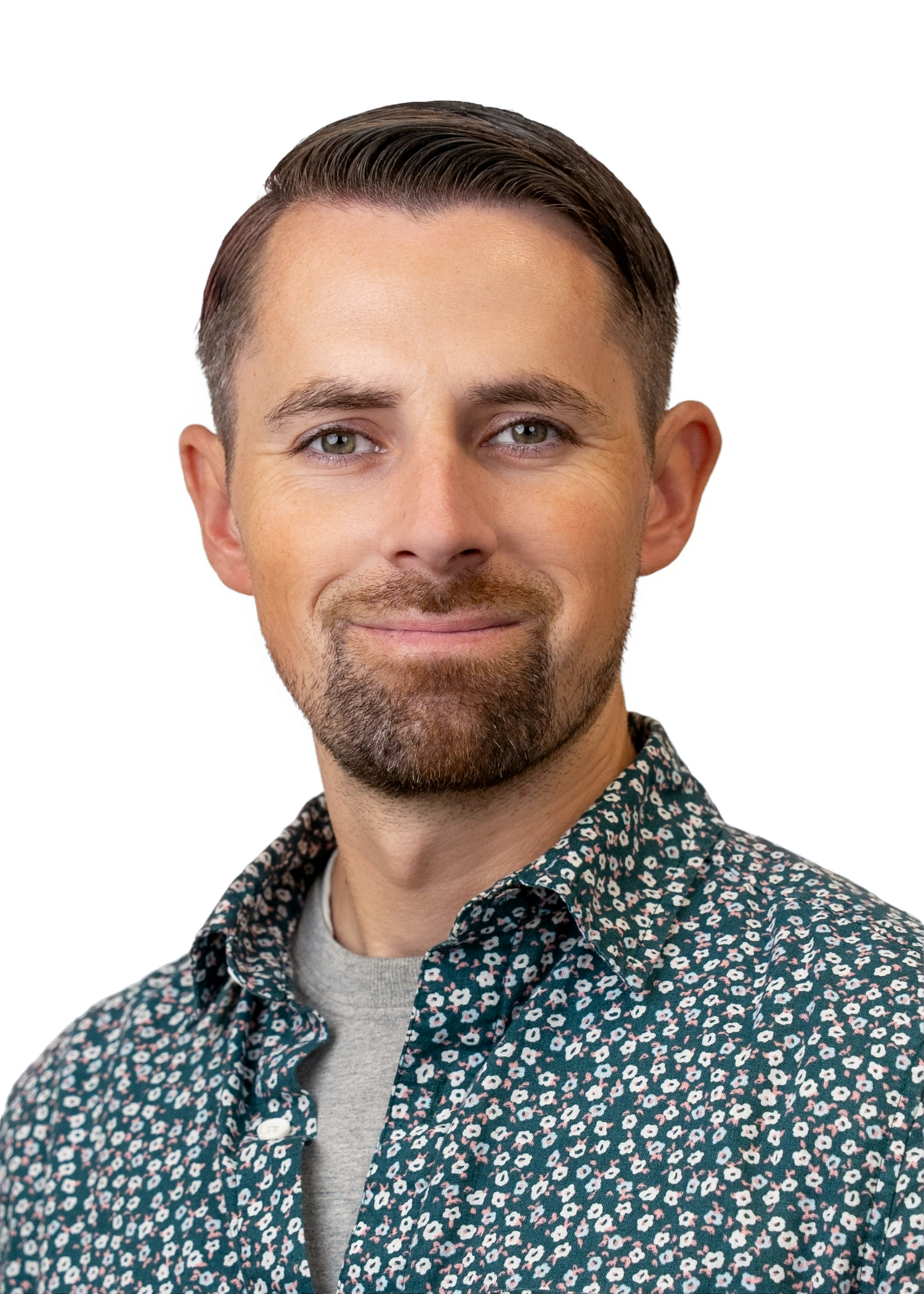 Our staff member: Portrait of a smiling man with a beard wearing a floral shirt, professional headshot.